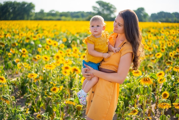 Heureuse mère et sa petite fille dans le champ de tournesol