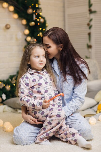 Heureuse mère avec sa petite fille enfant jouant près de l'arbre de Noël