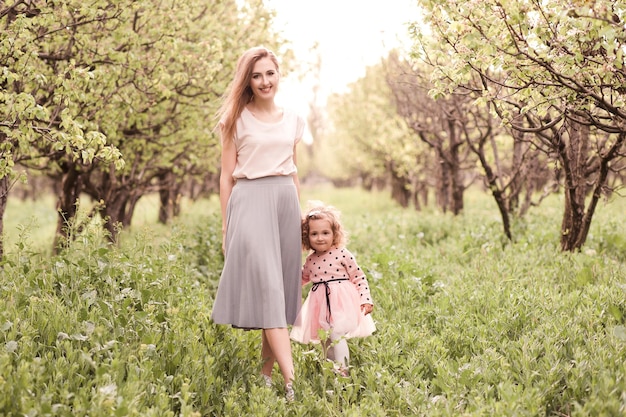 Heureuse mère avec sa petite fille posant dans le jardin