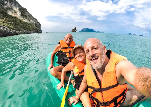 Heureuse mère senior et père avec fils prenant selfie lors d'une excursion en kayak en Thaïlande