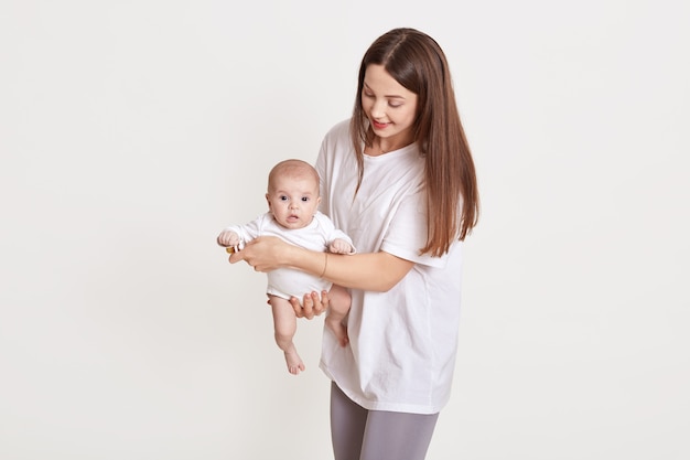 Heureuse mère avec son bébé posant isolé sur blanc