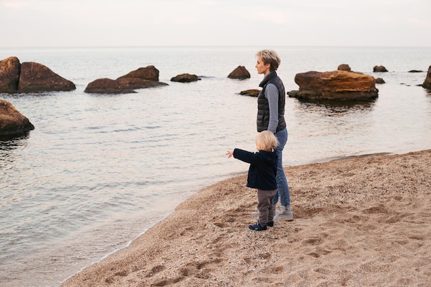 Heureuse mère avec son fils sur la plage près de la mer en automne