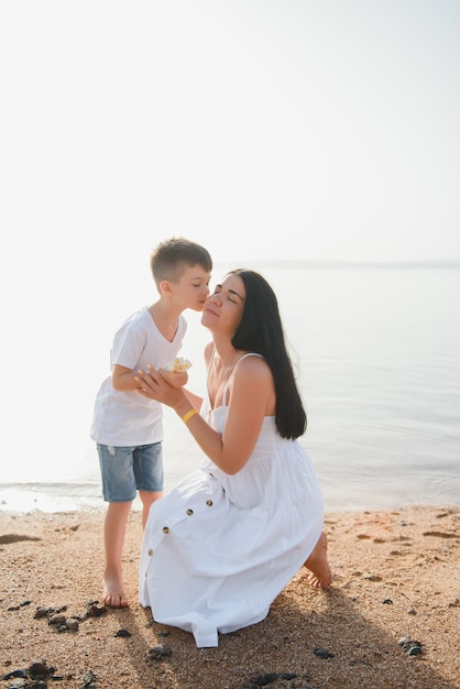 Heureuse mère avec son fils se donnant des baisers au bord de la plage