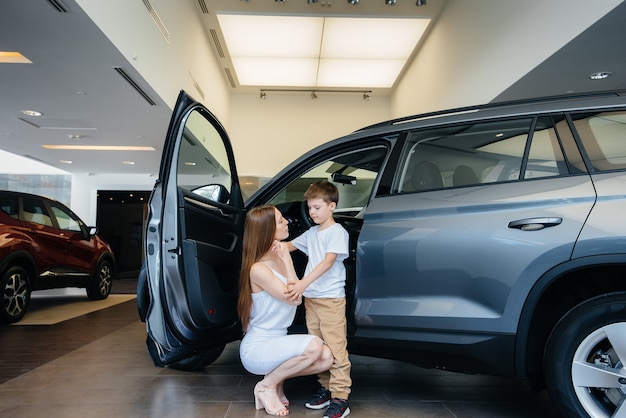 Heureuse mère avec son jeune fils choisit une nouvelle voiture chez un concessionnaire automobile