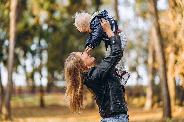 Heureuse mère avec son petit bébé s'amuser dans le parc de la ville