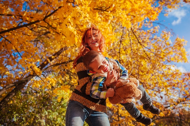 Heureuse mère et son petit fils marchant et s&#39;amusant dans la forêt d&#39;automne.