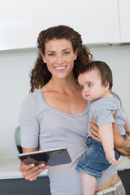 Heureuse mère avec tablette numérique portant bébé