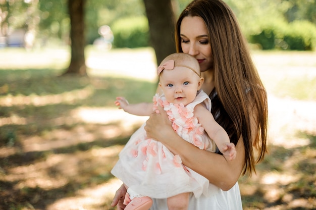 Heureuse mère tenant sa petite fille mignonne sur les mains dans le parc