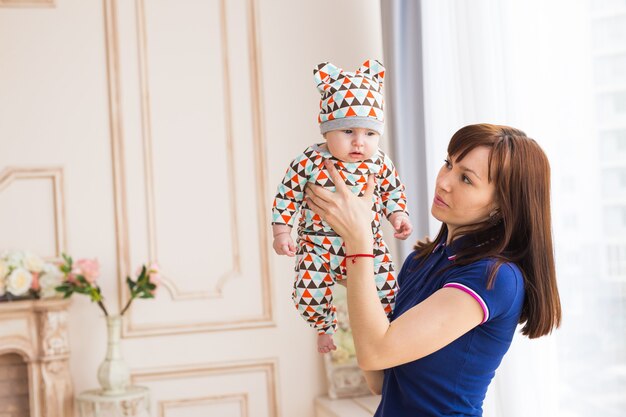 Heureuse mère tenant son bébé et jouant avec lui à l'intérieur