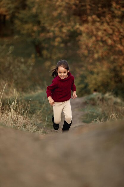 Heureuse petite fille adorable court dans le parc en automne