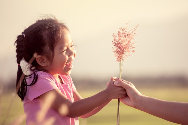 Heureuse petite fille asiatique donnant la fleur d&#39;herbe à sa mère avec amour dans le ton de couleur vintage
