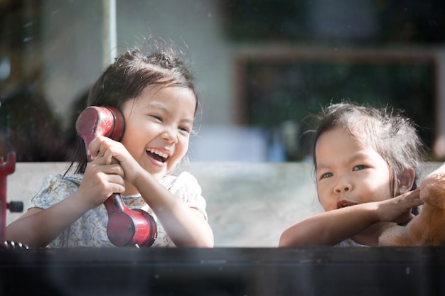 Heureuse petite fille asiatique jouant et parlant de téléphone au café dans le ton de couleur vintage