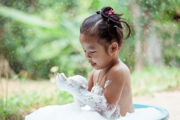 Heureuse petite fille asiatique s&#39;amuser et jouer avec de la mousse