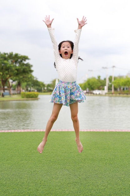 Heureuse petite fille asiatique sautant dans le jardin en plein air