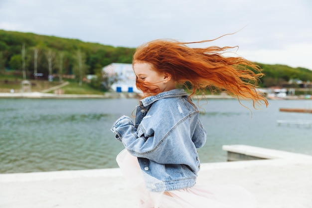 Heureuse petite fille aux cheveux rouges court le long de la plage enfant sur la plage