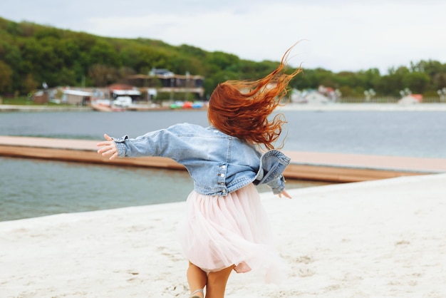 Heureuse petite fille aux cheveux rouges court le long de la plage enfant sur la plage