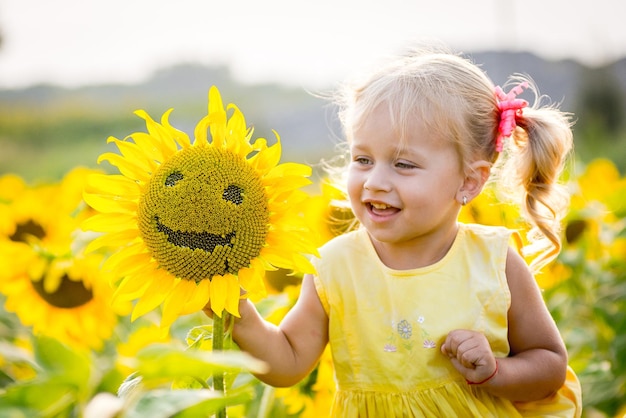 Photo heureuse petite fille sur le champ de tournesols en été belle petite fille en tournesols