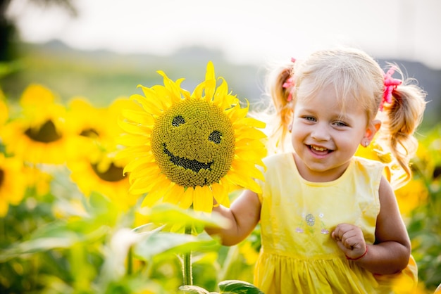Photo heureuse petite fille sur le champ de tournesols en été belle petite fille en tournesols