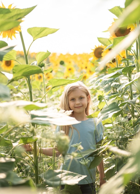 Heureuse petite fille sur le champ de tournesols en été.