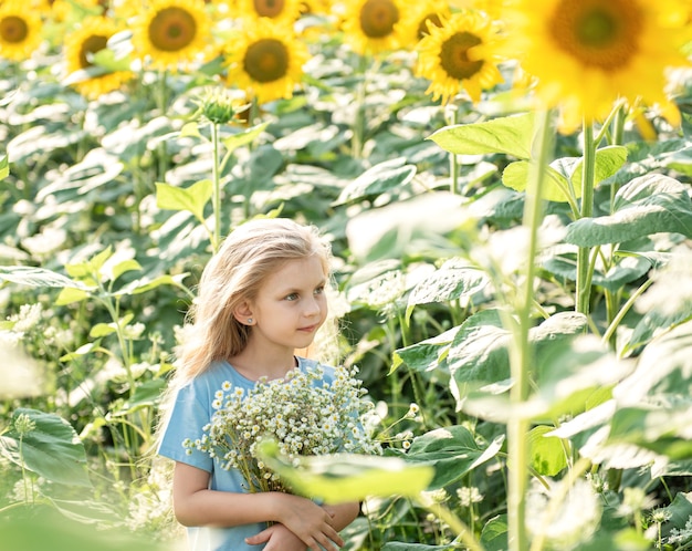 Heureuse petite fille sur le champ de tournesols en été.