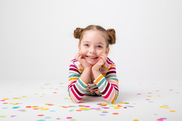 Heureuse petite fille avec des confettis sur fond blanc