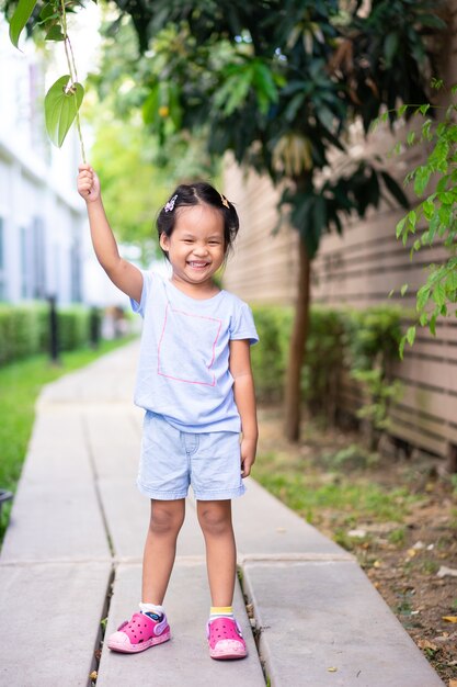 Heureuse petite fille debout sur un trottoir dans le parc