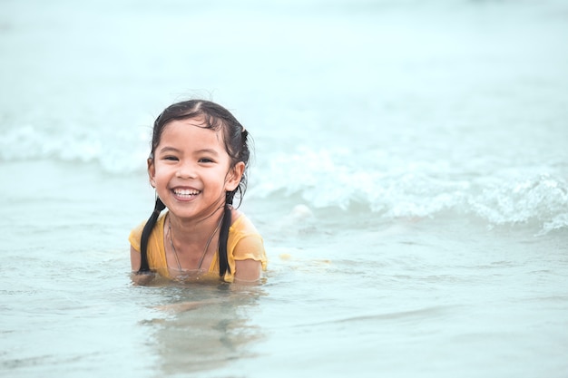 Heureuse petite fille enfant asiatique s&#39;amuser à jouer de l&#39;eau dans la mer en vacances d&#39;été