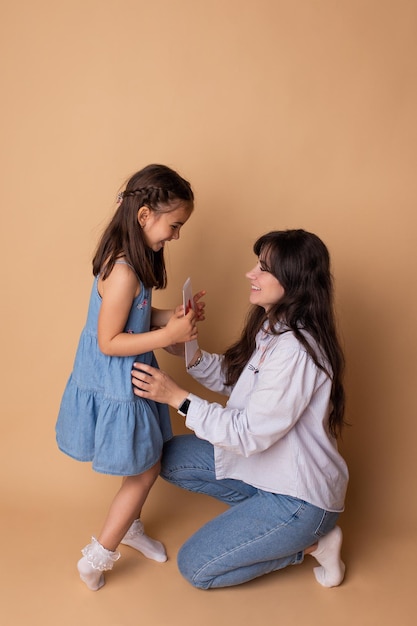 Heureuse petite fille félicitant mère souriante et donnant carte avec coeur rouge Concept famille heureuse