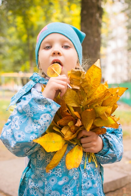 Heureuse petite fille avec les feuilles de l'automne dans le parc