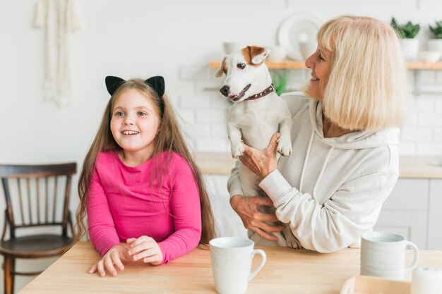 Heureuse petite-fille et grand-mère dans la cuisine avec grand-mère de chien jack russell terrier et