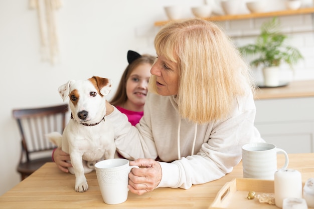 Heureuse petite-fille et grand-mère dans la cuisine avec grand-mère de chien jack russell terrier et