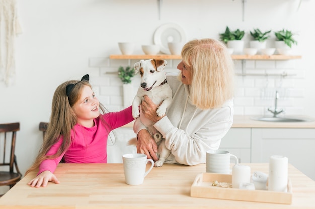 Heureuse petite-fille et grand-mère dans la cuisine avec grand-mère de chien jack russell terrier et