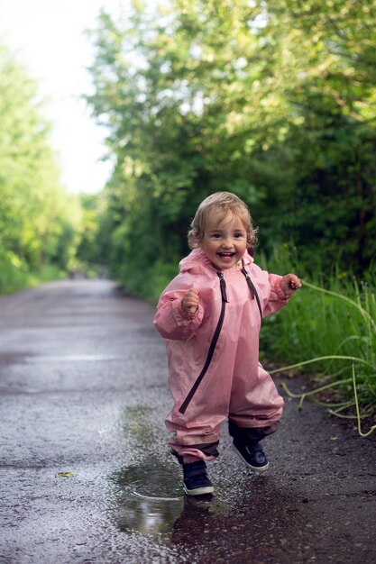 Photo heureuse petite fille insouciante qui traverse les flaques d'eau après la pluie en journée d'été