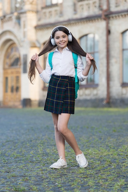 Heureuse petite fille insouciante de retour à l'école en écoutant de la musique, amusez-vous concept.