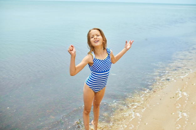 Heureuse petite fille joyeuse courir sur la plage