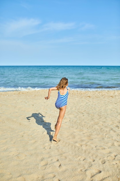 Heureuse petite fille joyeuse courir sur la plage