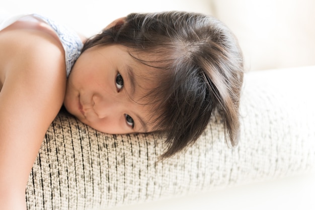 Heureuse petite fille mignonne couchée sur un canapé confortable à la maison.