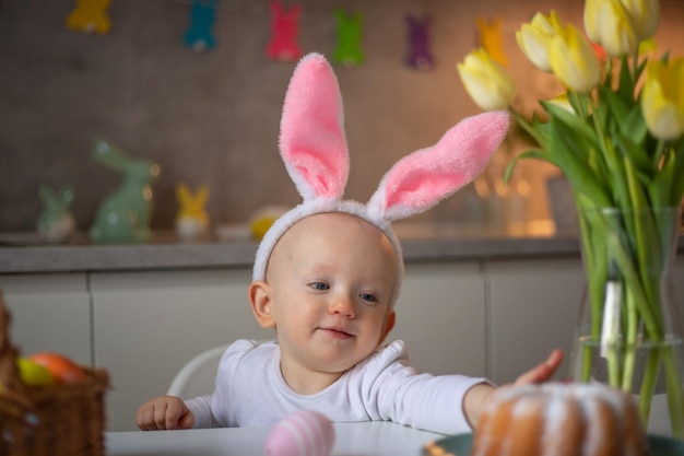 Heureuse petite fille mignonne portant des oreilles de lapin le jour de pâques assis à la table dans la cuisine