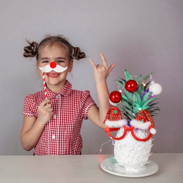 Heureuse petite fille mignonne près du visage du père noël fait avec de l'ananas