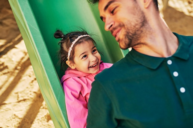 Heureuse petite fille mignonne souriant et jouant avec son père à l'extérieur Beau papa et petite fille en bas âge riant et s'amusant et jouant au terrain de jeux