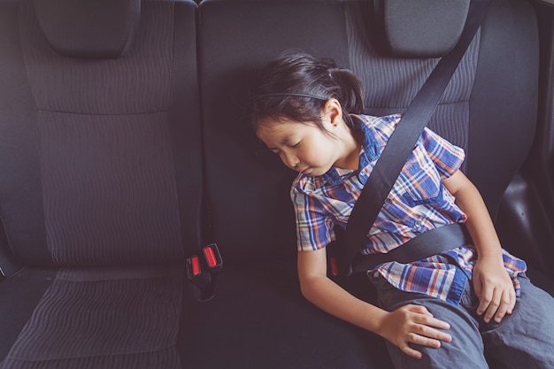 Heureuse petite fille portant la ceinture de sécurité en voiture