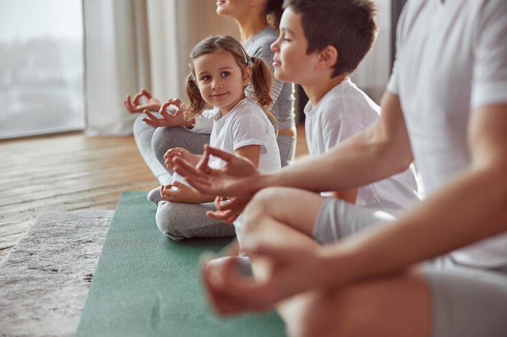 Heureuse petite fille pratiquant la méditation en famille