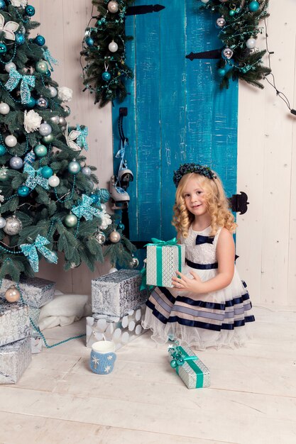 Heureuse petite fille en robe avec un cadeau de Noël