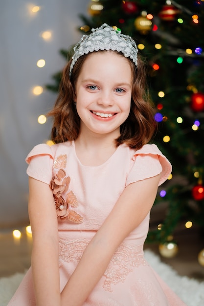 heureuse petite fille en robes roses à l'arbre de noël