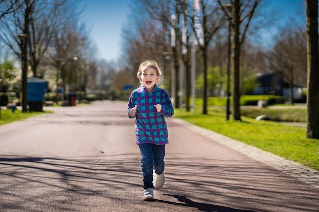 Heureuse petite fille souriante petite fille courant au coucher du soleil mignonne petite fille courant au jardin de l'aire de jeux