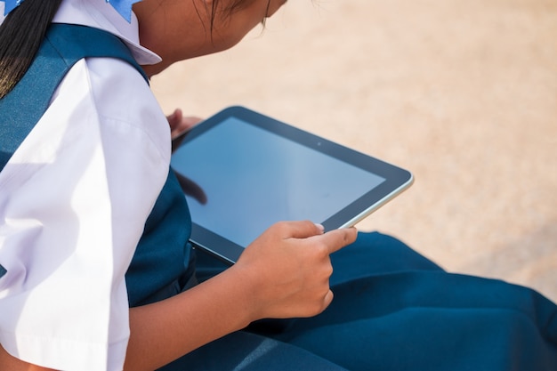 Heureuse petite fille tenant une tablette PC à l&#39;extérieur dans le parc de l&#39;été