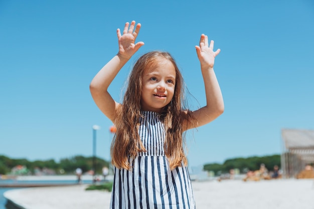 Heureuse petite fille trisomique s'amusant sur la plage