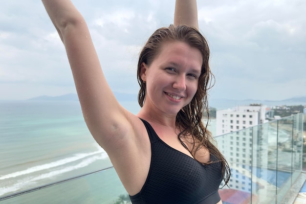 Heureuse positive belle fille jeune femme profite des vacances d'été dans la piscine spa de luxe sur le toit de l'hôtel dans un pays tropical exotique avec vue sur l'océan mer respirer profondément profondément l'air frais