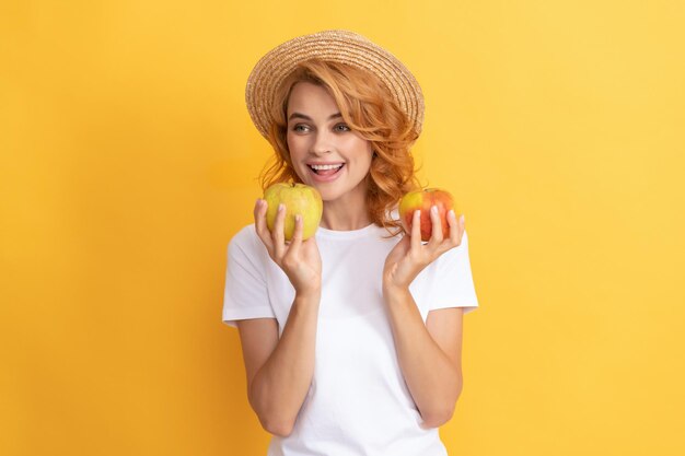 Heureuse rousse au chapeau de paille tenir apple detox