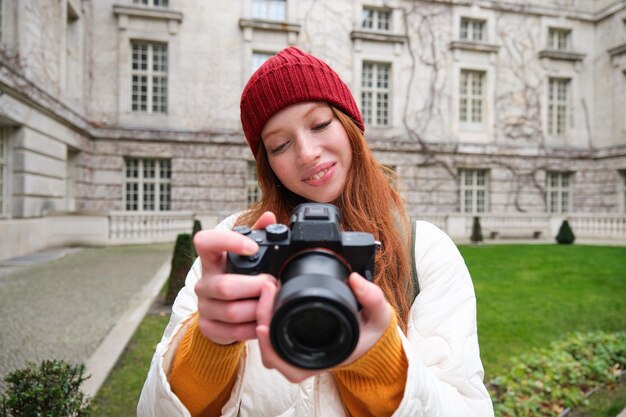 Heureuse rousse touriste prend des photos photographe avec appareil photo professionnel se promène dans la ville et